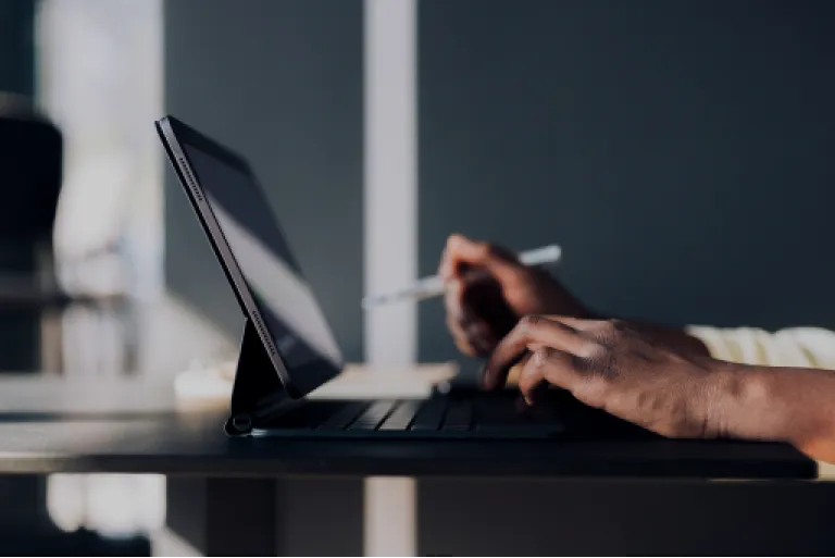 Close-up of a person's hands working at a tablet computer