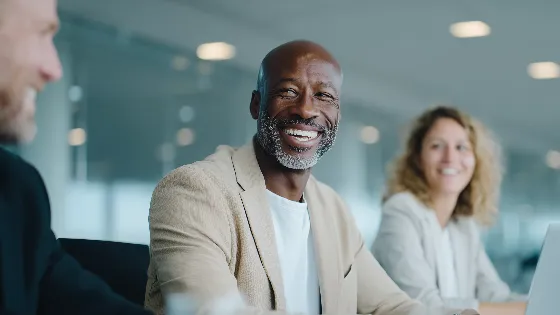 3 professionals laugh during a relaxed and engaging conversation
